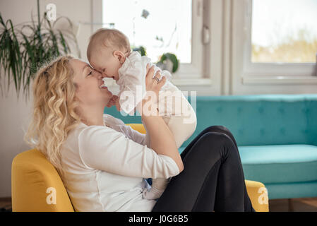 Mutter und Baby Kopf-an-Kopf sitzen am gelben Sessel Stockfoto
