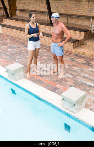 Schwimmen Sie Trainer, die Interaktion mit älteren Mann am Pool Stockfoto