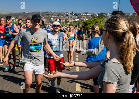 Menschen vor Ort bieten Süßigkeiten an die Athleten die Teilnahme In Brighton Marathon, Brighton, Sussex, Großbritannien Stockfoto