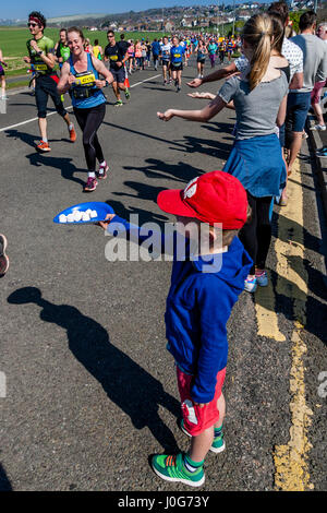 Ein kleiner Junge bietet Süßigkeiten an die Athleten die Teilnahme In Brighton Marathon, Brighton, Sussex, Großbritannien Stockfoto