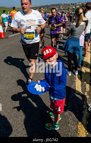 Ein kleiner Junge bietet Süßigkeiten an die Athleten die Teilnahme In Brighton Marathon, Brighton, Sussex, Großbritannien Stockfoto