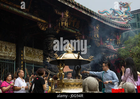 Eine Menge Leute mit Weihrauch beten klebt durch eine goldene Weihrauch-Brenner an der Mengjia Longshan Tempel in Taipei, Taiwan. Stockfoto