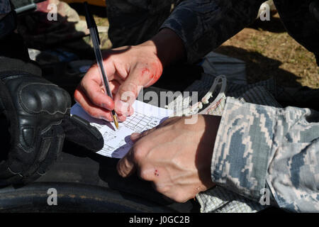 Techn. Sgt. Christian Gomez, 569th US Kräfte Polizei Squadron Bravo Flug Chef, schreibt die Verletzungen von einem simulierten verletzten Flieger während der tactical combat Casualty Care Teil des 435. Sicherheit Kräfte Squadron Ground Combat Readiness Training Center Security Operations Kurs auf Ramstein Air Base, Deutschland, 30. März 2017. Während der TCCC Teil hatten die Schüler gemeinsam sichern, das simulierte Opfer Hilfe leisten, fordern eine medizinische Evakuierung, bewegen das Opfer auf einen Wurf und laden Sie sie in einem simulierten Hubschrauber. Flieger, 86. SFS, 422. S zugewiesen Stockfoto