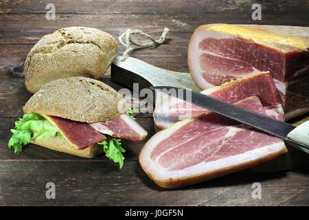 Italienischer trocken geheilt Schinken mit Brot Brötchen auf hölzernen Hintergrund Stockfoto