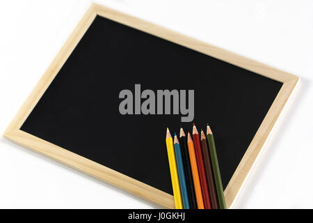 Farbstiften am schwarzen Brett isoliert auf weißem Hintergrund Stockfoto