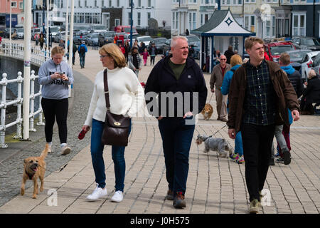 Aberystwyth Wales UK, Donnerstag, 13. April 2017 UK Wetter: Menschen zu Fuß auf der Strandpromenade promenade an einem kalten aber hellen und luftigen Tag in Aberystwyth, Wales, am Vorabend von Ostern Bank Holiday Wochenende Foto Credit: Keith Morris/Alamy Live News Stockfoto