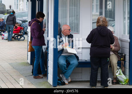 Aberystwyth Wales UK, Donnerstag, 13. April 2017 UK Wetter: Menschen essen Fisch und Chips direkt am Meer promenade an einem kalten aber hellen und luftigen Tag in Aberystwyth, Wales, am Vorabend von Ostern Bank Holiday Wochenende Foto Credit: Keith Morris/Alamy Live News Stockfoto