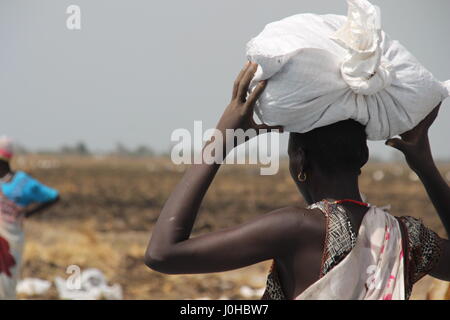 Ganyliel, Süd-Sudan. 24. März 2017. Eine Frau trägt einen Beutel mit Hilfsgütern auf dem Kopf in Ganyliel, Süd-Sudan, 24. März 2017. Es befindet sich im sudanesischen Bundesstaat Unity, der Region von Hungersnot im Land am stärksten betroffen. Foto: Jürgen Bätz/Dpa/Alamy Live News Stockfoto