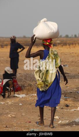Ganyliel, Süd-Sudan. 24. März 2017. Eine Frau trägt einen Beutel mit Hilfsgütern auf dem Kopf in Ganyliel, Süd-Sudan, 24. März 2017. Es befindet sich im sudanesischen Bundesstaat Unity, der Region von Hungersnot im Land am stärksten betroffen. Foto: Jürgen Bätz/Dpa/Alamy Live News Stockfoto