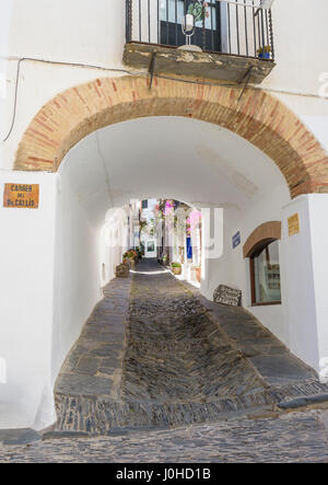 Einen Bogen Gang durch eine weiß getünchte Gebäude entlang der Carrer des nennen, bekannt für seine Fischgräten Rastell Kopfsteinpflaster Bürgersteig, Cadaques, Katalonien, Spanien Stockfoto