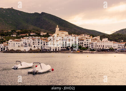 Sonnenuntergang über den weiß getünchten Dorf Cadaqués, gekrönt von der Kirche Santa Maria mit Blick auf Boote in Cadaques Bucht, Katalonien, Spanien Stockfoto