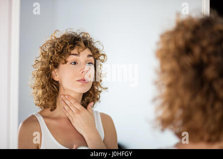 lockiges Mädchen mit Hautcreme auf in einem Spiegel Stockfoto