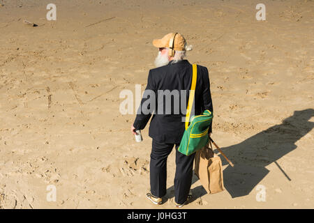 Ein älterer Mann steht am Sandstrand neben dem Fluss Themse in der Nähe von Londons South Bank. Stockfoto