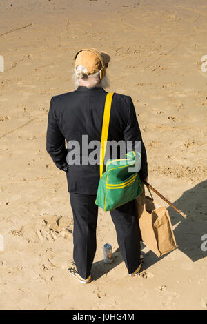 Ein älterer Mann steht am Sandstrand neben dem Fluss Themse in der Nähe von Londons South Bank. Stockfoto