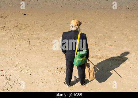 Ein älterer Mann steht am Sandstrand neben dem Fluss Themse in der Nähe von Londons South Bank. Stockfoto