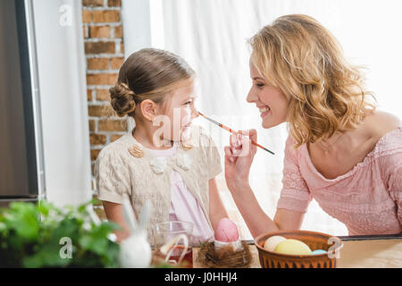 Junge Mutter und ihre süße Tochter Spaß beim Ostereier für Ostern Stockfoto