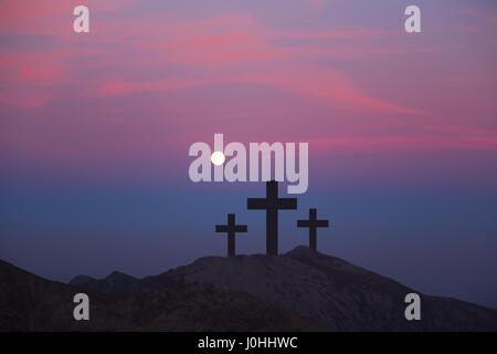 Kreuze auf dem Hügel über Sonnenuntergang Hintergrund. Religiöse Konzept der Kreuzigung Stockfoto