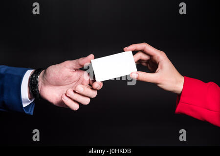 Close-up Teilansicht des männlichen und weiblichen Hände halten leere Karte auf schwarz Stockfoto