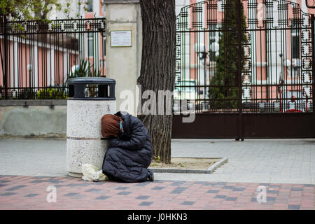 Obdachlose Bettler Frau sitzt auf dem Asphalt fordern Geld für Lebensmittel Stockfoto