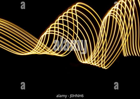 Gold Licht Malerei Fotografie, wirbelt vor einem schwarzen Hintergrund. Lange Belichtung Foto, abstrakte neon Gold Farbe parallel line Pattern. Stockfoto