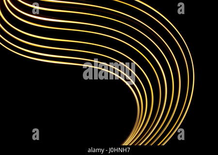 Gold Licht Malerei Fotografie, wirbelt vor einem schwarzen Hintergrund. Lange Belichtung Foto, abstrakte neon Gold Farbe parallel line Pattern. Stockfoto