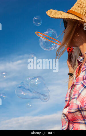 Junge Frau trägt machen Seife Blasenmenge Strohhut Stockfoto