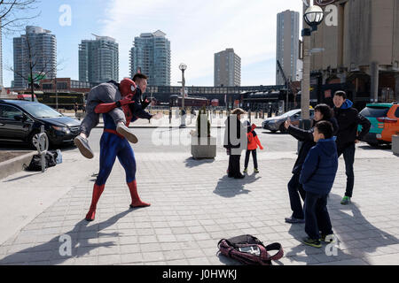 Straßenkünstler, verkleidet als Spider-man, posiert für Touristenfotos, hebt einen asiatischen Touristen vom Boden, Street Life, Toronto, Ontario, Kanada Stockfoto