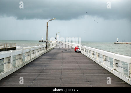 Blick auf den Pier im November mit Mann Angeln und dunkle Wolken Regen angekündigt Stockfoto