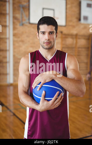 Porträt von entschlossen Basketball-Spieler hält einen Basketball im Hof Stockfoto