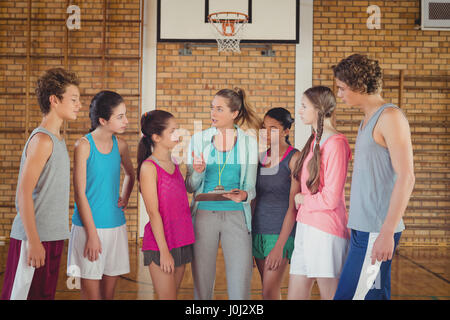 Weibliche Trainer mentoring High-School-Kids in Basketballplatz Stockfoto