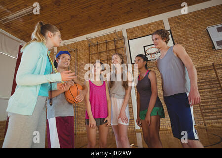 Weibliche Trainer mentoring High-School-Kids in Basketballplatz Stockfoto