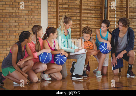 Weibliche Trainer mentoring High-School-Kids in Basketballplatz Stockfoto