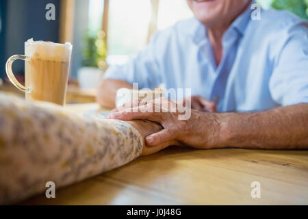 Älteres Paar Hand in Hand beim Kaffeetrinken in CafÃƒÂ © Stockfoto