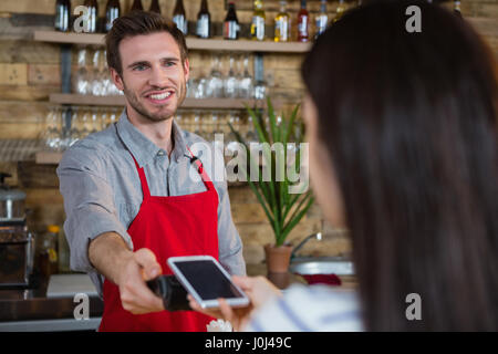 Frau, die die Zahlung durch NFC-Technologie auf dem Handy in CafÃƒÂ © Stockfoto