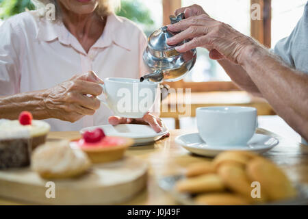 Senior Mann Gießen Tee in die Tasse am CafÃƒÂ © Stockfoto