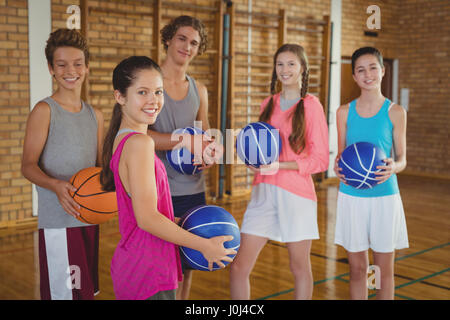 Porträt der High School kids Holding Basketball zusammen im Hof Stockfoto