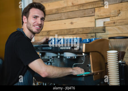 Porträt von lächelnden Kellner Reinigung Kaffeemaschine am Schalter im café Stockfoto