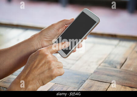 Abgeschnitten Bild senior Frau mit Smartphone auf Holztisch Stockfoto