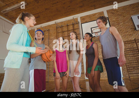 Weibliche Trainer mentoring High-School-Kids in Basketballplatz Stockfoto