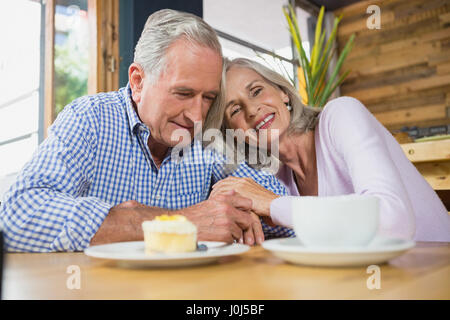 Gerne älteres Paar umarmen einander in CafÃƒÂ © Stockfoto