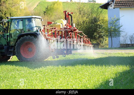 Ein Traktor Sprühen von Pestiziden in der Nähe von Häusern Stockfoto