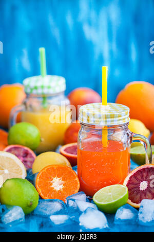 Zitrusfrüchte Vitamin Saft in Einweckgläser mit frischen Orangen, Mandarinen, Zitronen und Limetten herum, gesundes Getränk Stockfoto