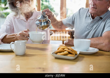 Senior Mann Gießen Tee in die Tasse am CafÃƒÂ © Stockfoto