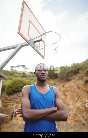 Porträt von männlichen Basketballspieler stehend mit seinen gekreuzten im Hof Stockfoto