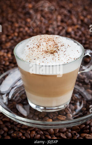 Tasse frische heiße Latte auf Kaffeebohne Hintergrund Stockfoto