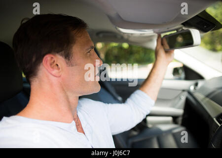 Junger Mann Anpassung Rückspiegel im Auto Stockfoto