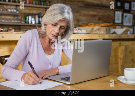 Aufmerksame senior Frau arbeitet in CafÃƒÂ © Stockfoto