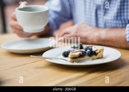 Mittleren Teil des senior Mann hält eine Kaffeetasse im café Stockfoto