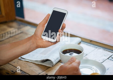 Beschnitten, Bild Frau mit Handy beim Kaffeetrinken am Tisch Stockfoto