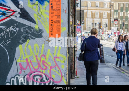 Eine Frau geht vorbei an einer großen Wand auf Hanbury Street im Osten Londons, der in der Straßenkunst fällt. Stockfoto